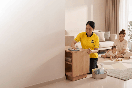 Part-time helper cleaning while mother plays with baby on floor in Singapore home